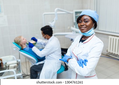 Portrait of Female black dentist in dental office. She standing at her office and she has beautiful smile. Modern medical equipment - Shutterstock ID 1304761261