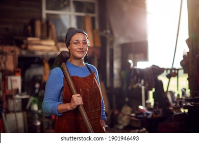 Portrait Of Female Blacksmith Holding Hammer Standing In Forge - Powered by Shutterstock