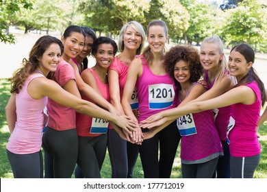 Portrait of female breast cancer marathon runners stacking hands in park