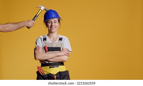 Portrait of female builder being hit in head and feeling dizzy, seeing stars in eyes and acting disorientated or light headed. Unsteady shaky woman feeling weak and wobbly, looney tunes. - Shutterstock ID 2213262559