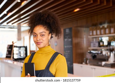 Portrait Of Female Business Owner Of Coffee Shop In Mask Using Digital Tablet During Health Pandemic