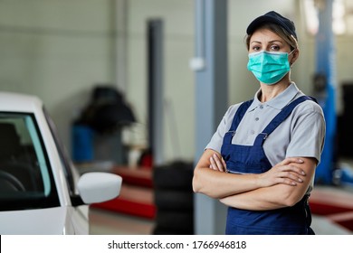 Portrait of female car mechanic standing with arms crossed while wearing protective face mask at workshop.  - Powered by Shutterstock