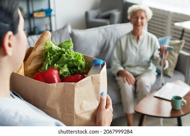 Portrait Of Female Caregiver Bringing Groceries To Senior Woman, Copy Space