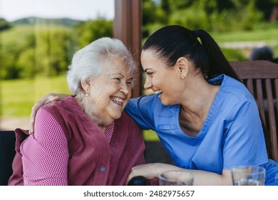 Portrait of female caregiver and senior woman. Nurse and elderly woman enjoying a warm day in nursing home, public park. - Powered by Shutterstock