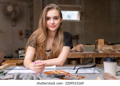 Portrait Of A Female Carpenter Drawing On Paper For Designing And Building Furniture In A Furniture Factory. With Modern Tools