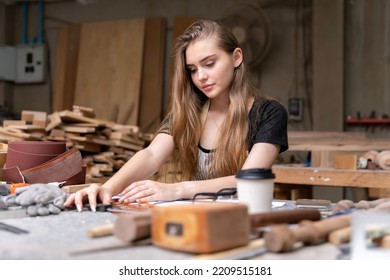 Portrait Of A Female Carpenter Drawing On Paper For Designing And Building Furniture In A Furniture Factory. With Modern Tools