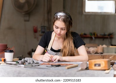 Portrait Of A Female Carpenter Drawing On Paper For Designing And Building Furniture In A Furniture Factory. With Modern Tools