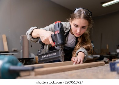 Portrait Of A Female Carpenter Using Tools For Making Furniture In A Furniture Factory. With Modern Tools