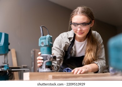 Portrait Of A Female Carpenter Using Tools For Making Furniture In A Furniture Factory. With Modern Tools