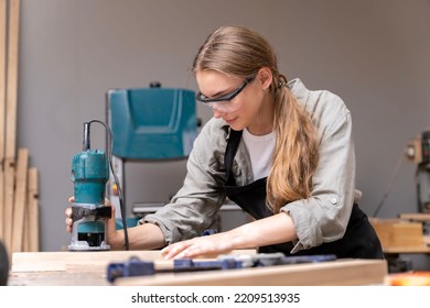 Portrait Of A Female Carpenter Using Tools For Making Furniture In A Furniture Factory. With Modern Tools