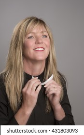 Portrait Of A Female Clergy Wearing A Black Shirt And Holding A Clerical Collar Which She Is Attaching To Her Shirt