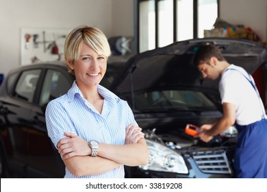 portrait of female client with arms folded in auto repair shop. - Powered by Shutterstock