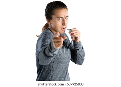 Portrait of female coach gesturing while holding whistle against white background - Powered by Shutterstock