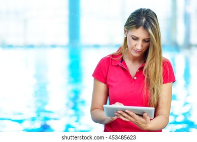 Portrait of female coach with a stop watch and clipboard by pool at leisure center - Powered by Shutterstock