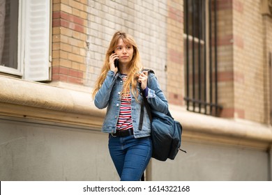 Portrait Of Female College Student Walking And Talking With Cellphone Outside