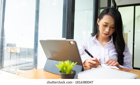Portrait of female concentrating on her work with books, laptop and supplies on worktable in the office. - Shutterstock ID 1816380047