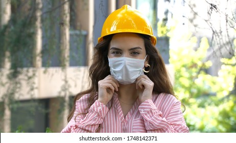 Portrait Of Female Construction Worker In Medical Mask And Overalls On Background Of House Under Construction.