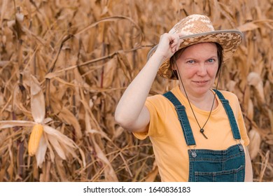 Portrait Of Female Corn Farmer In Field Wearing Straw Hat And Bib Overalls