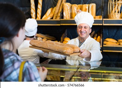 Portrait of female customer buying fresh bread from cheerful baker
 - Powered by Shutterstock