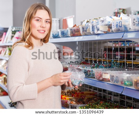 
Portrait of  female customer picking   variety candies in cellophane bag  in store