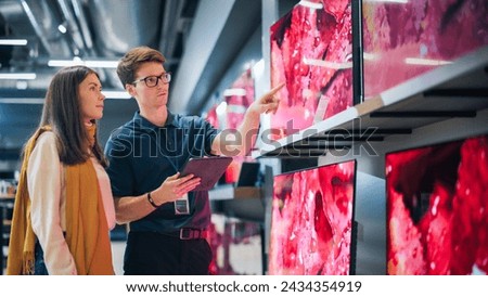 Portrait of a Female Customer Seeking Advice from Retail Home Electronics Expert. Young Lady Explores Modern TV Options. Shopper Evaluating Latest Television Innovations in Elegant Department Store
