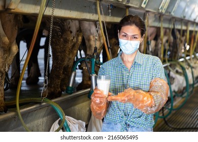 Portrait Of Female Dairy Farm Worker In Protective Mask Standing With Glass Of Fresh Milk