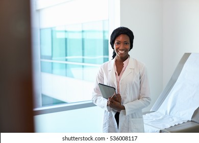 Portrait Of Female Doctor With Digital Tablet In Exam Room