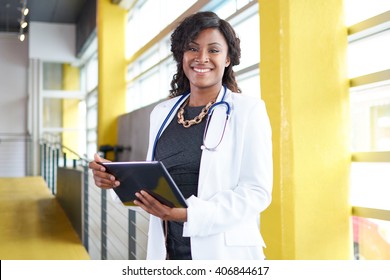 Portrait of a female doctor holding her patient chart on digital tablet in bright modern hospital