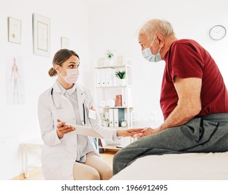 Portrait Of A Female Doctor Holding A Tablet And Senior Patient Wearing Protective Masks At Her Doctor's Office In Clinic