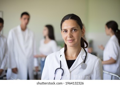 Portrait of female doctor in hospital. Group of people in patient room. 