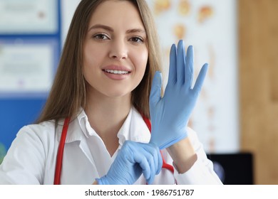 Portrait Of Female Doctor Putting On Medical Gloves