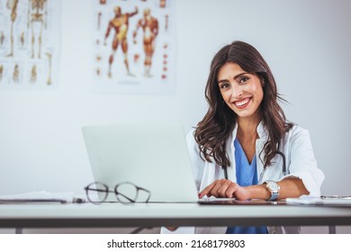 Portrait of female doctor seating in her office at clinic. Friendly Latin American female doctor at the hospital looking at the camera and smiling. Confident female doctor at office desk