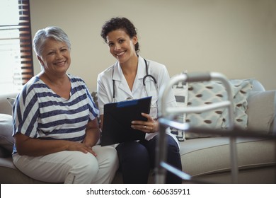 Portrait of female doctor with senior woman in living room at home - Shutterstock ID 660635911