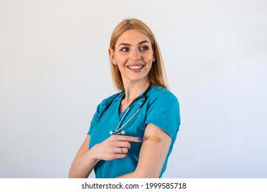 Portrait Of A Female Doctor Smiling After Getting A Vaccine. Medical Worker Showing Her Arm With Bandage After Receiving Vaccination.