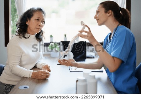 Portrait of a female doctor talking to an elderly patient about herniated disc deterioration from long hours of work