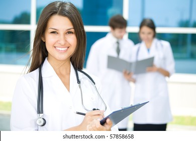 Portrait of a female doctor with two of her co-workers against modern hospital building - Powered by Shutterstock