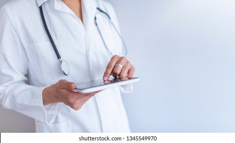 Portrait of female doctor using her digital tablet in the office. Close-up of a female doctor using tablet PC. A picture of a doctor holding tablet over white background  - Powered by Shutterstock