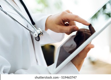 Portrait of female doctor using her digital tablet in the office. - Shutterstock ID 519463747
