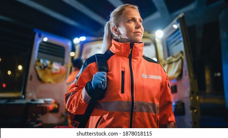 Portrait of a Female EMS Paramedic Proudly Standing in Front of Camera in High Visibility Medical Orange Uniform with "Paramedic" Text Logo. Successful Emergency Medical Technician or Doctor at Work.