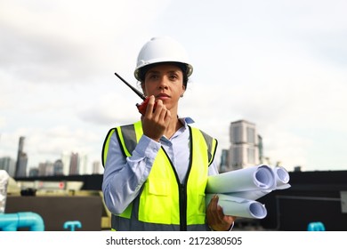 Portrait Female Engineer With Green Reflex Safety Vest And White Hard Hat Stand Holding Drawing And Using Walkie Talkie Communicaton With Team 