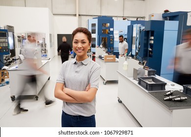 Portrait Of Female Engineer On Factory Floor Of Busy Workshop