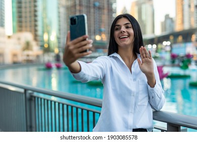 Portrait Female Entrepreneur Using Video Call At Street. Sexy Businesswoman Using Smartphone In Black Dress Outdoors. Attractive Woman Touching Hair With Phone In Hand Outside.