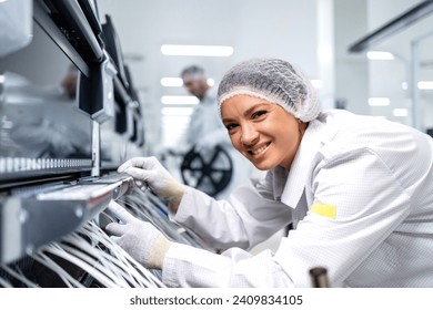 Portrait of female factory worker in anti-static suit connecting wires on assembly line in automotive industry production. - Powered by Shutterstock