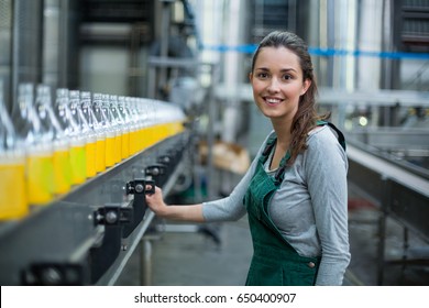 Portrait of female factory worker standing near production line at drinks production factory - Powered by Shutterstock