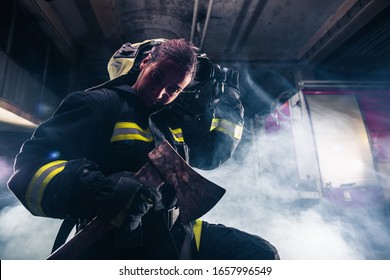 Portrait Of A Female Firefighter While Holding An Axe And Wearing An Oxygen Mask Indoors Surrounded By Smoke.