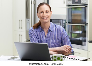 Portrait Of Female Freelance Worker Using Laptop In Kitchen At Home