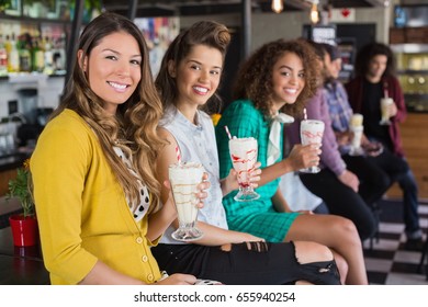 Portrait of female friends drinking smoothie at restaurant - Powered by Shutterstock