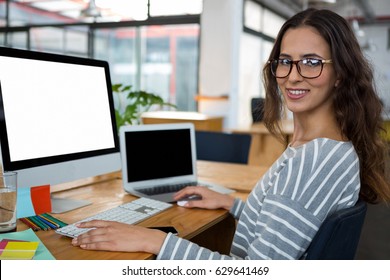 Portrait Of A Female Graphic Designer Working At Desk In Creative Office