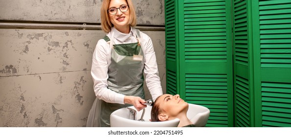 Portrait Of Female Hairdresser Washing Hair Of The Young Caucasian Woman In A Beauty Salon