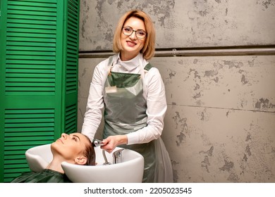 Portrait Of Female Hairdresser Washing Hair Of The Young Caucasian Woman In A Beauty Salon